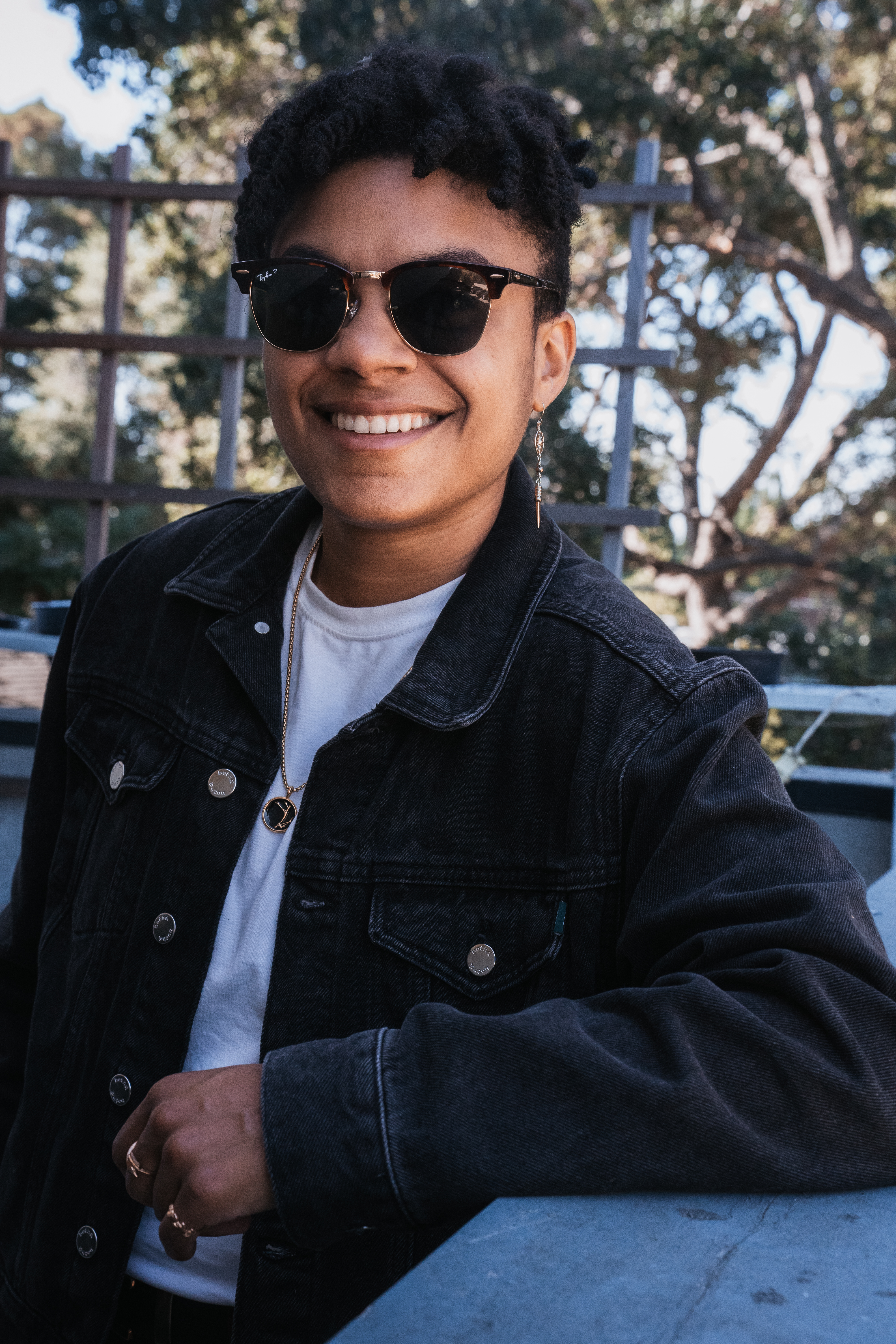 photo of Jackie outside, in sunglasses and a black denim jacket over a white shirt